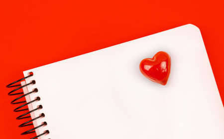 Notebook with red heart on it, love letter background concept with red table and copy space, top viewの写真素材
