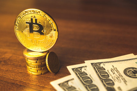 Shiny golden bitcoin coin and dollar bills on a wooden table, concept of big growth of the...