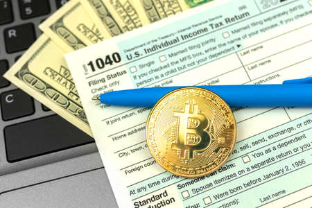 Paying the taxes by crypto currency, 1040 US Individual Income Tax Return from next to bitcoin coinの写真素材