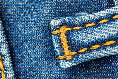 Blue denim jeans with orange thread stitches close-up, casual and urban classic fashion conceptの写真素材
