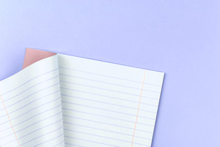 Opened lined notebook for school on a pastel purple background of office table desktop, copy space...