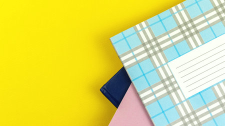 A lot of school diary on yellow bright table background, top view with copy space