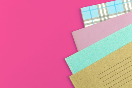 Many school notebooks on pink table offide desktop background, school concept flat lay backgroundの写真素材