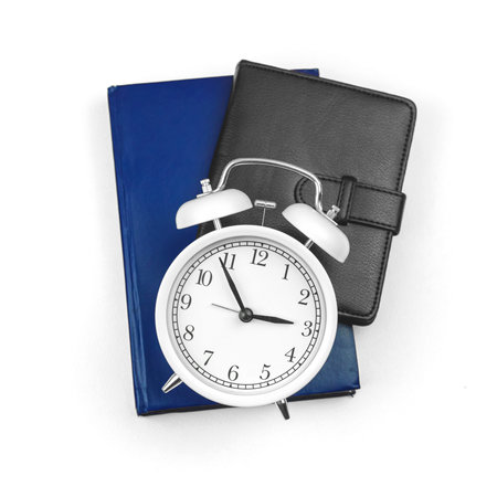 School education minimalistic concept background with alarm clock and notepads copybooks on white...