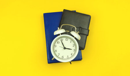 Concept of back to school, students education time background with alarm clock and diary notebooks...
