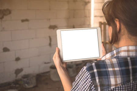 A young girl is planning the construction and renovation of a house concept, mockup tablet screen with blank white screen in hand, copy space photoの写真素材