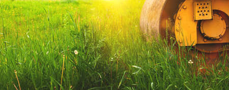Plot of land for construction site, banner with heavy machinery at sunset, green field background, copy spaceの写真素材