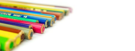 Education background with many different color pencils on a white table, isolated, copy space