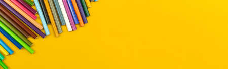 School stationery long banner with many color drawing pencils, yellow desktop background with copy space, top viewの写真素材