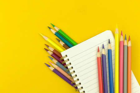 Back to school composition with notepad and color drawing pencils, education concept, yellow desktop background, top viewの写真素材