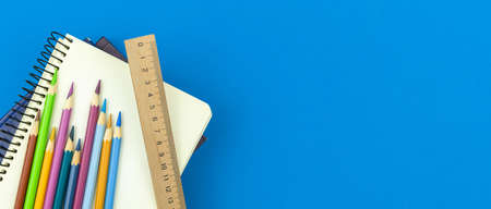 School stationery and supplies flat lay background, blue desktop with notepad, color drawing pencils and a wood ruler, top view and copy space bannerの写真素材