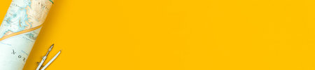 Flat lay school geography wide web banner with copy space and world map on the yellow table desktop, top viewの写真素材