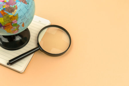 Archeology flat lay background, school education and lessons concept, the glove with magnifying glass on the beige table, top viewの写真素材