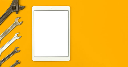 Service worker mockup concept, tablet blank white screen with wrench tools on the table, yellow background, top view, flat lay and copy spaceの写真素材