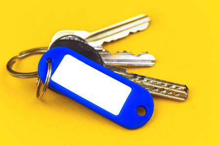 Keys with mockup plastic badge with copy space, concept of new property purchasing, yellow background photoの写真素材