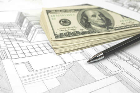 Working on construction project background. Office table with dollars and pen on sketchesの写真素材