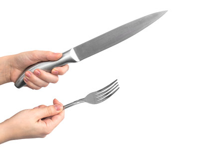 Kitchen utensil. Stainless steel knife and fork in woman hand, isolated on a white background