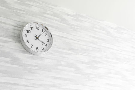 Time management concept background with clock on gray wall, copy space, bright photo