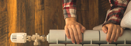 Banner woman hand on heating radiator in apartment modern interior background with copy space photo