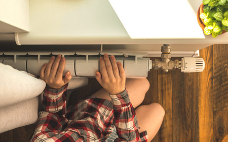 Girl with bare feet beside the radiator heater in modern home interior background