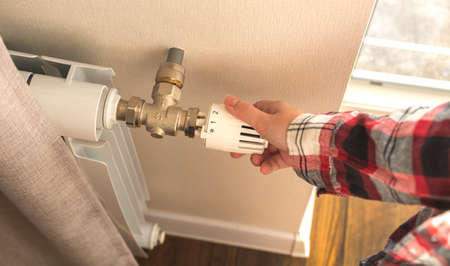 Woman adjusting heating radiator thermostat indoors photoの写真素材