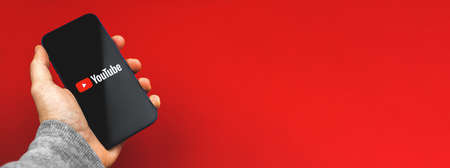 Kharkov, Ukraine - March 24, 2021: person using mobile phone with Youtube app, banner and copy space photoのeditorial素材