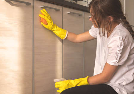 Young woman cleaning kitchen cabinet doors indoors at home, closeup viewの写真素材