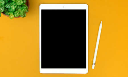 Top view workspace on yellow desktop with tablet and stylus pencil, copy spaceの写真素材