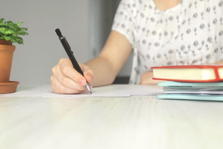 Close-up woman with pencil writing, on wooden table. Education, learning and document signing...