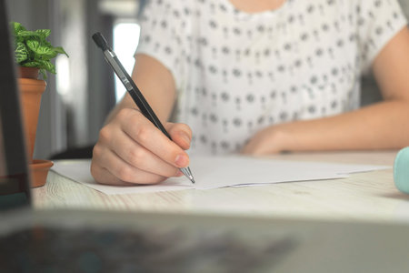 Female hands with pen writing on document. Office desk workspace background