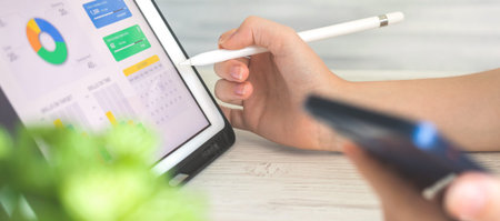 Banner worker analyzing company perfomance on digital tablet pc using stylus pen. Business and...