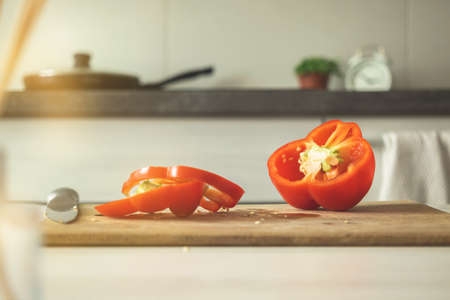 Cutting board with red pepper on a modern kitchen background. Sliced sweet bell pepper on wooden board. Vegetable ingredient, cooking healthy food conceptの写真素材