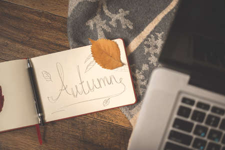 Hand written Autumn word with autumn leaves. Cozy home backgroundの写真素材