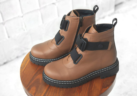 Brown women boots. Female autumn and winter footwear on a wooden stand. Modern design