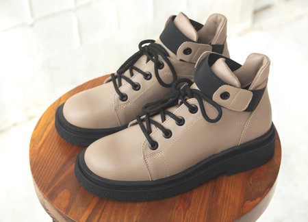 Leather women boots. Female autumn and winter footwear on a wooden stand. Modern design