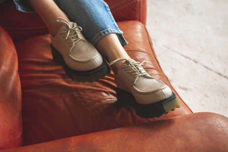 Luxurious photo of casual sneakers on teen girl sitting on old and retro armchair, studio shotの写真素材