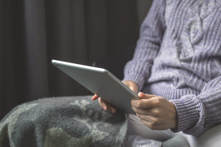 Woman resting in living room with tablet pc in hands, cozy home, reading concept