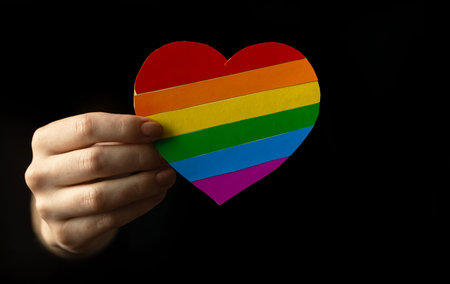 LGBT colorful heart in hand close-up on a black background