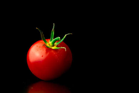 Washed cherry tomatoes on a black background, tomatoes with water droplets close-up view. Healthy eating conceptの写真素材