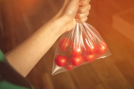 Fresh tomatoes in bag on kitchen background photoの写真素材