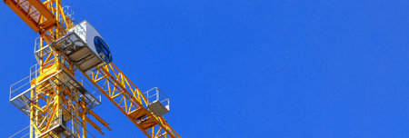 Construction crane cabin, yellow construction crane banner photo with blue sky background and copy spaceの写真素材