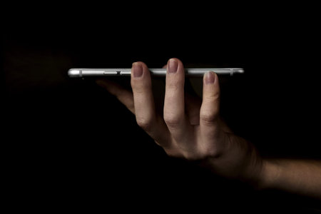 Woman hands using modern mobile phone on black background photo