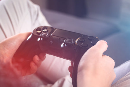 Female hands holding gaming controller. Concept of modern streaming and gaming with big tv sitting...