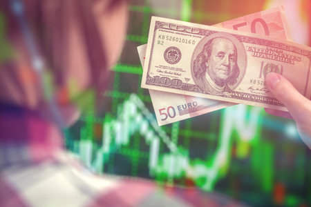 Trading and financial risk concept background. Businesswoman holding euro and US dollar money on a stock chart dynamics of exchange rates backdropの写真素材
