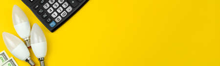 Energy saving. Calculator, LED light bulbs and money. Yellow background, banner, flat layの写真素材