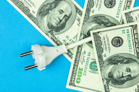 Green energy, saving energy concept. Electrical power cable with EU plug and dollar bills. Blue background with copy space photoの写真素材