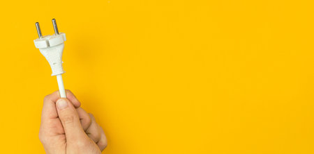 Electrical power cable in hand, banner. Orange background, flat lay, top view and copy space
