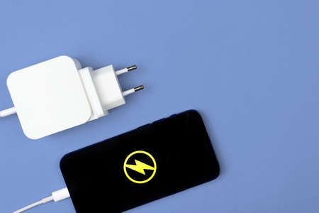Mobile charger. Smartphone with energy icon and power charger on bright background. Top view, flat layの写真素材