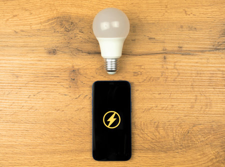 LED light bulb and mobile phone on a wooden table. Energy saving concept. Top viewの写真素材