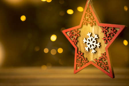 Christmas decoration background. Wooden star closeup, blurred christmas lights and bokehの写真素材